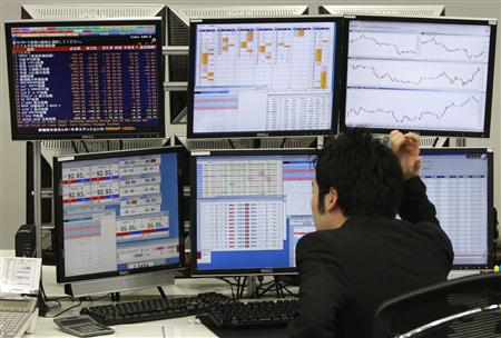 Trader looks at monitors in a dealing room in Tokyo
